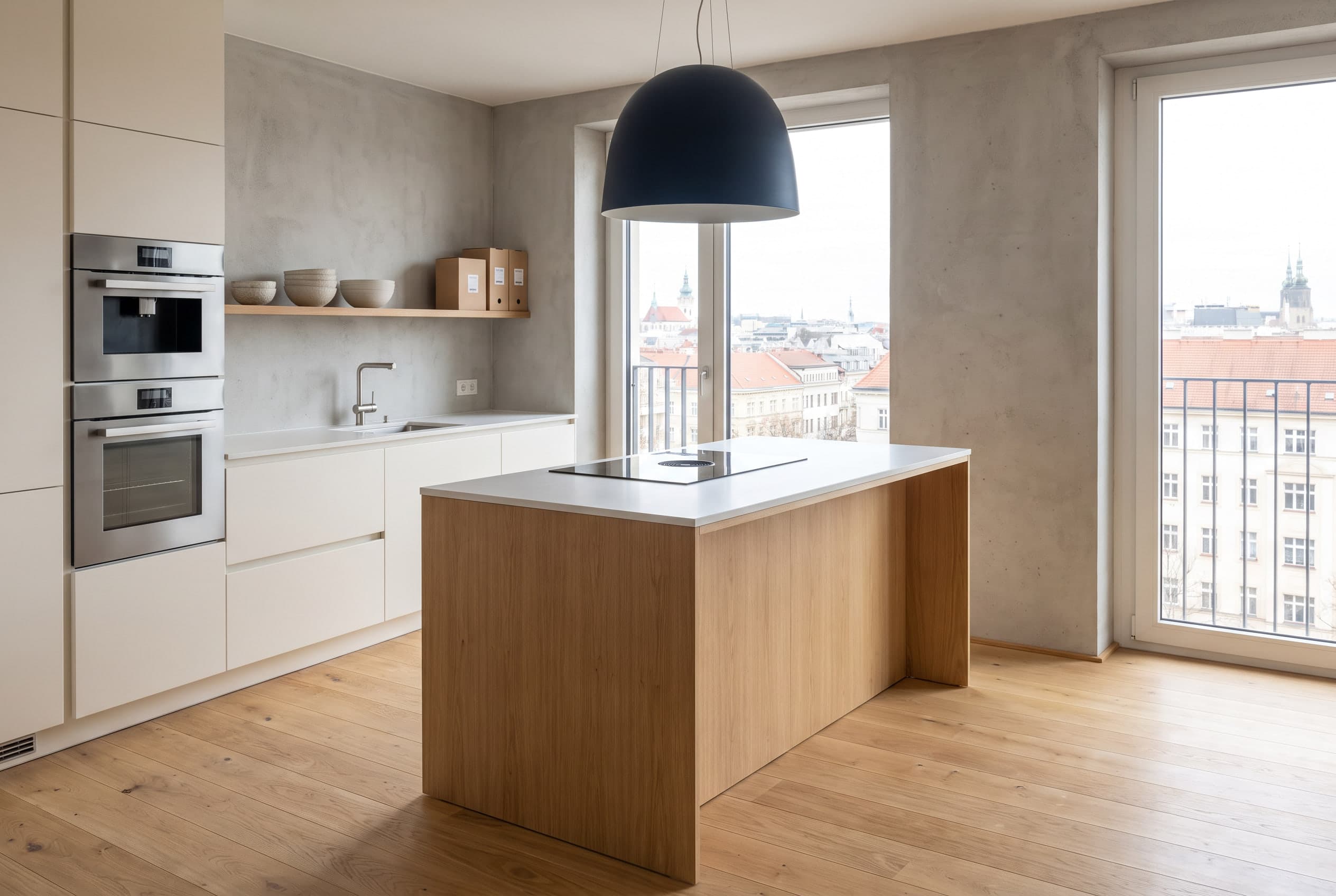 Opleveringsklare keuken in een appartement met witte fronten, inbouwapparatuur en een licht eiken kookeiland.